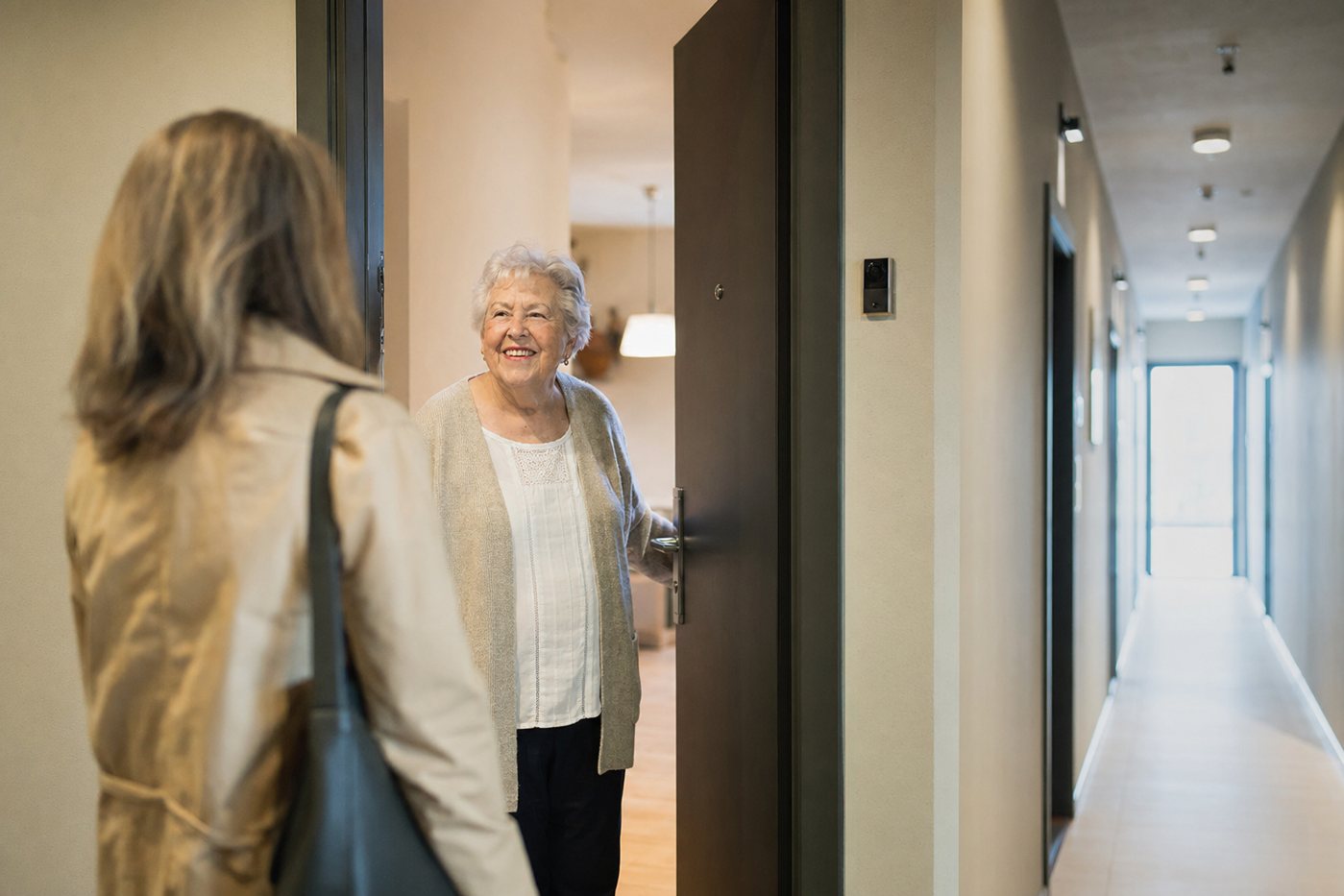 Senior woman at a well-lit apartment doorway